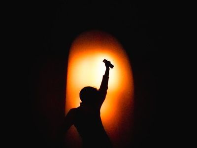Silhouette of a person in a powerful yoga stance against a dark background.